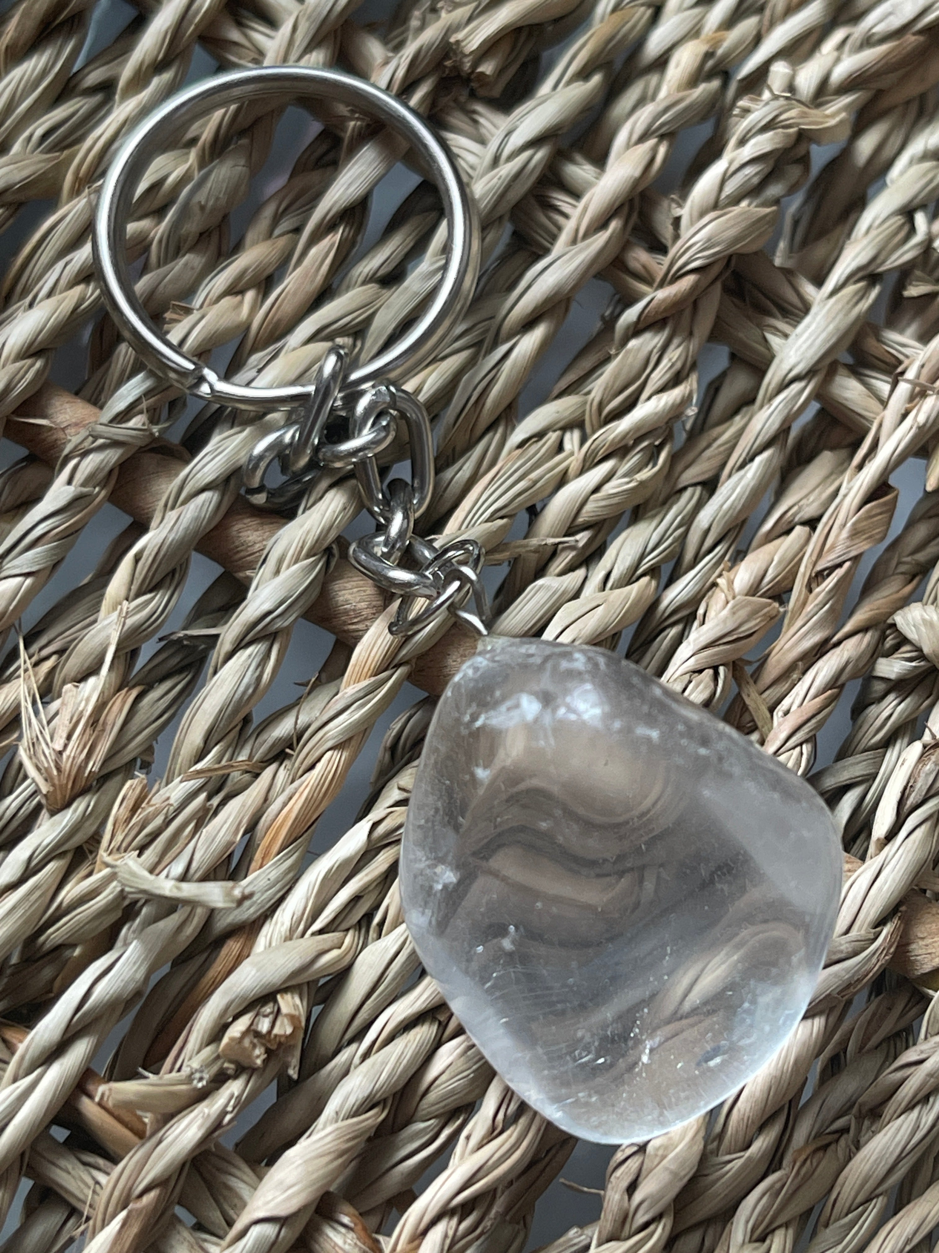 Clear stone with a keychain on a woven surface