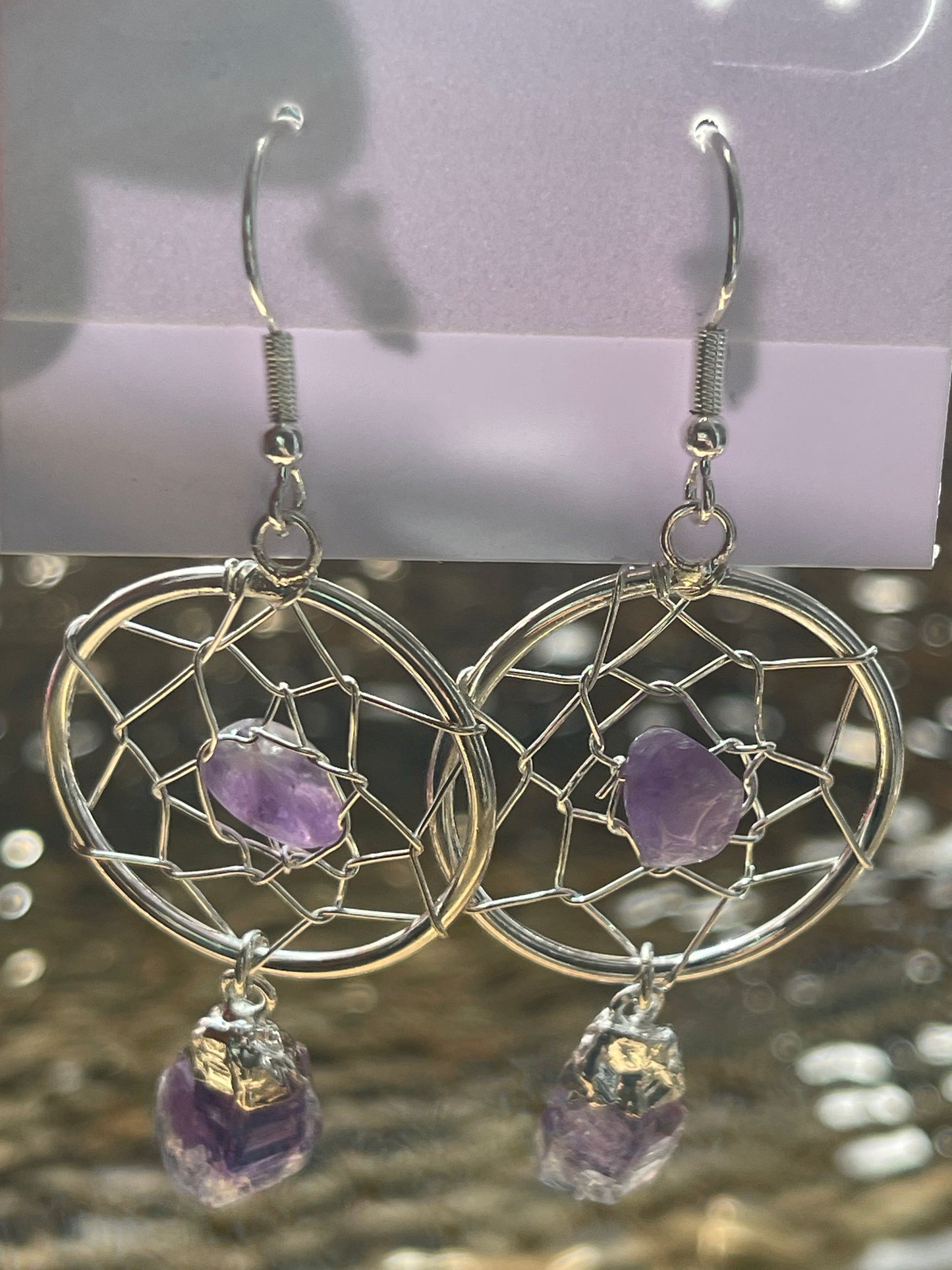 Dream Catcher Earrings, Silver dreamcatcher earrings with purple stones on a blurred background