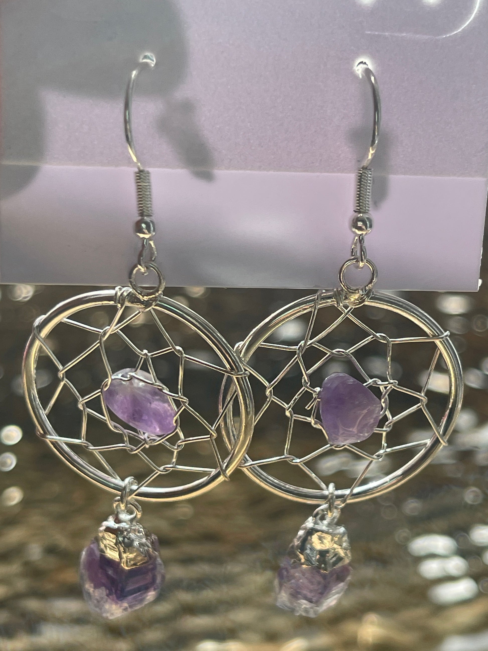 Dream Catcher Earrings, Silver dreamcatcher earrings with purple stones on a blurred background