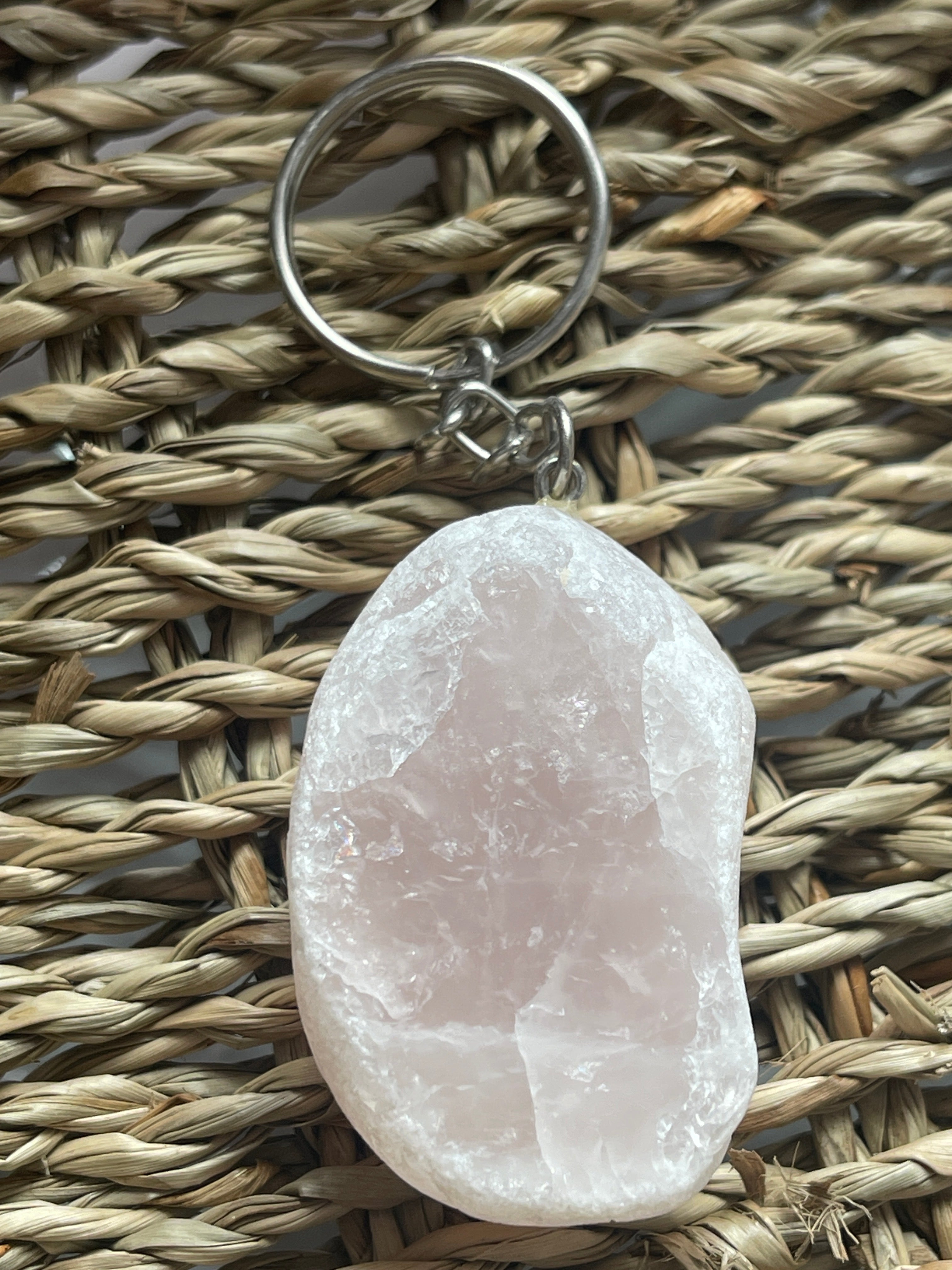 Pink Ema Egg Seer Stone Polished Keychain crystal keychain on a woven surface