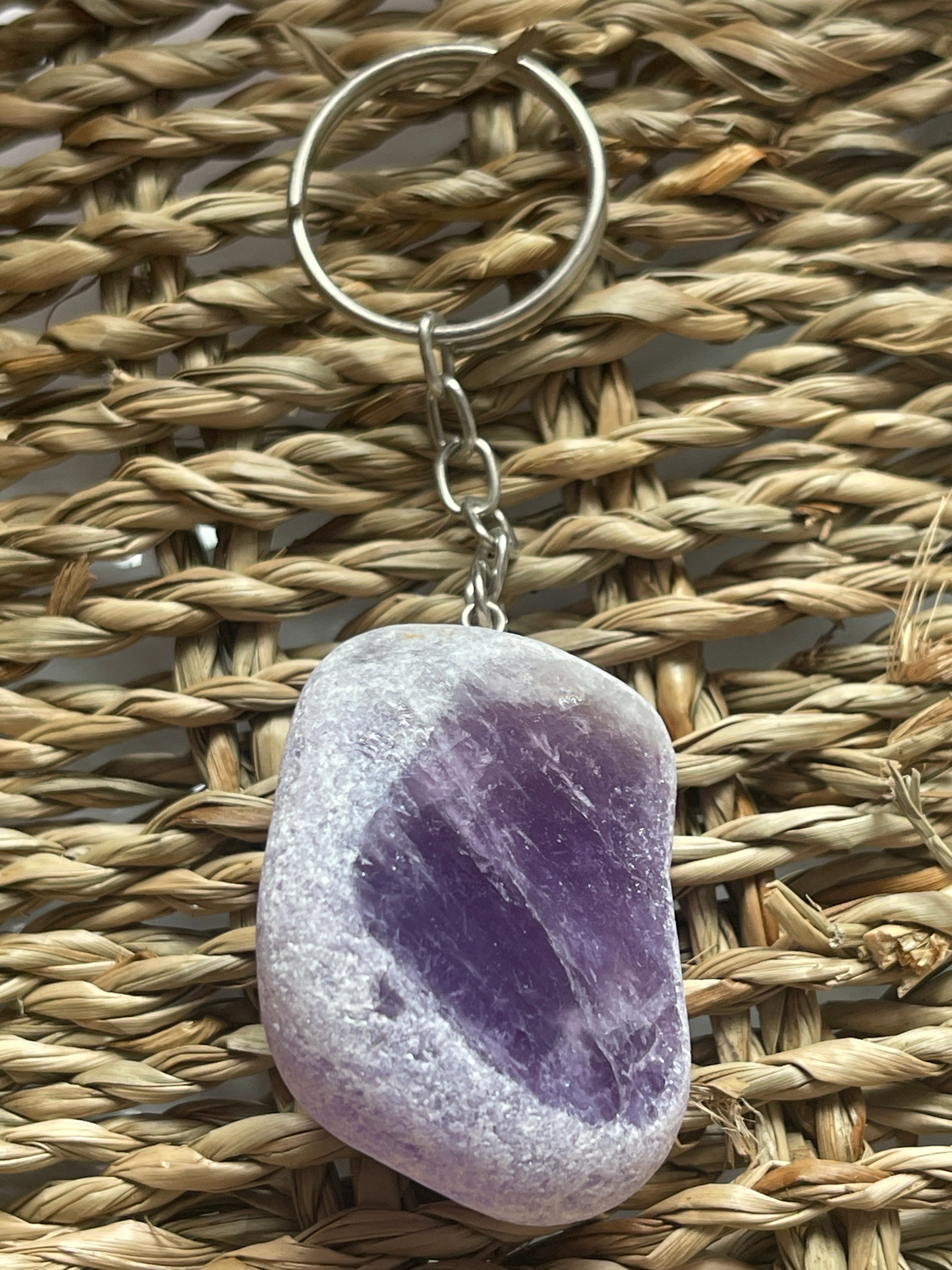 Purple stone Ema Egg Seer Stone Polished Keychain on a woven surface