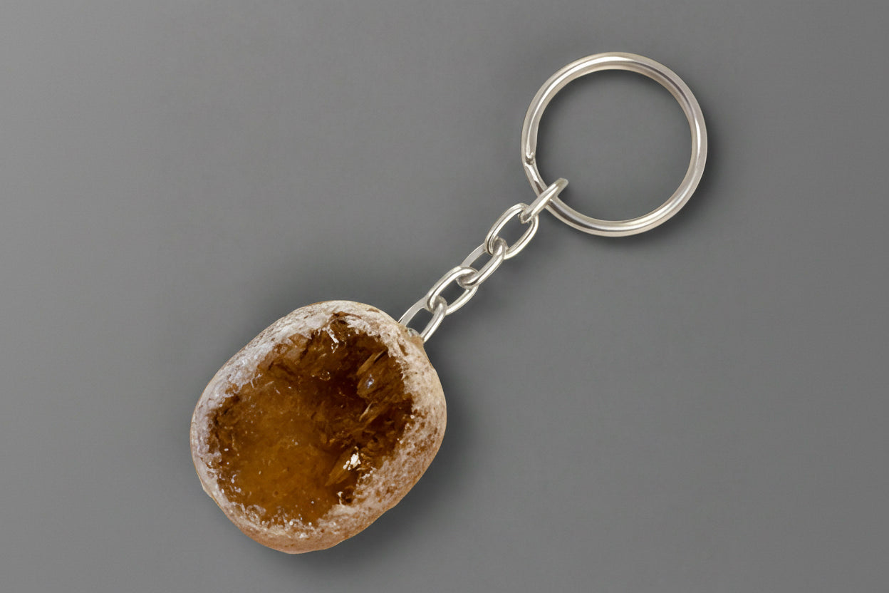 A polished keychain made of Ema Egg Seer Stone attached to a metal keyring, displayed against a gray background.