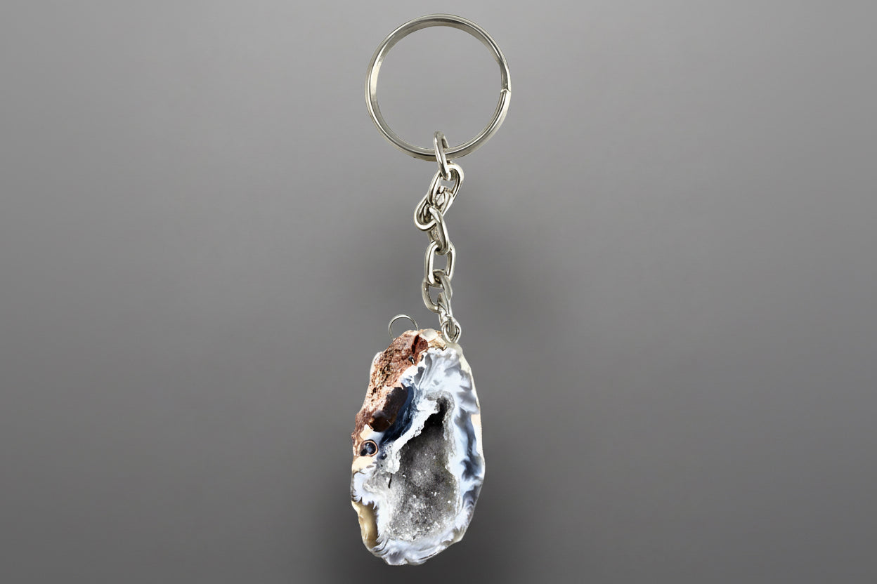 A polished natural geode key chain with vibrant colors and intricate patterns, attached to a metal keyring.