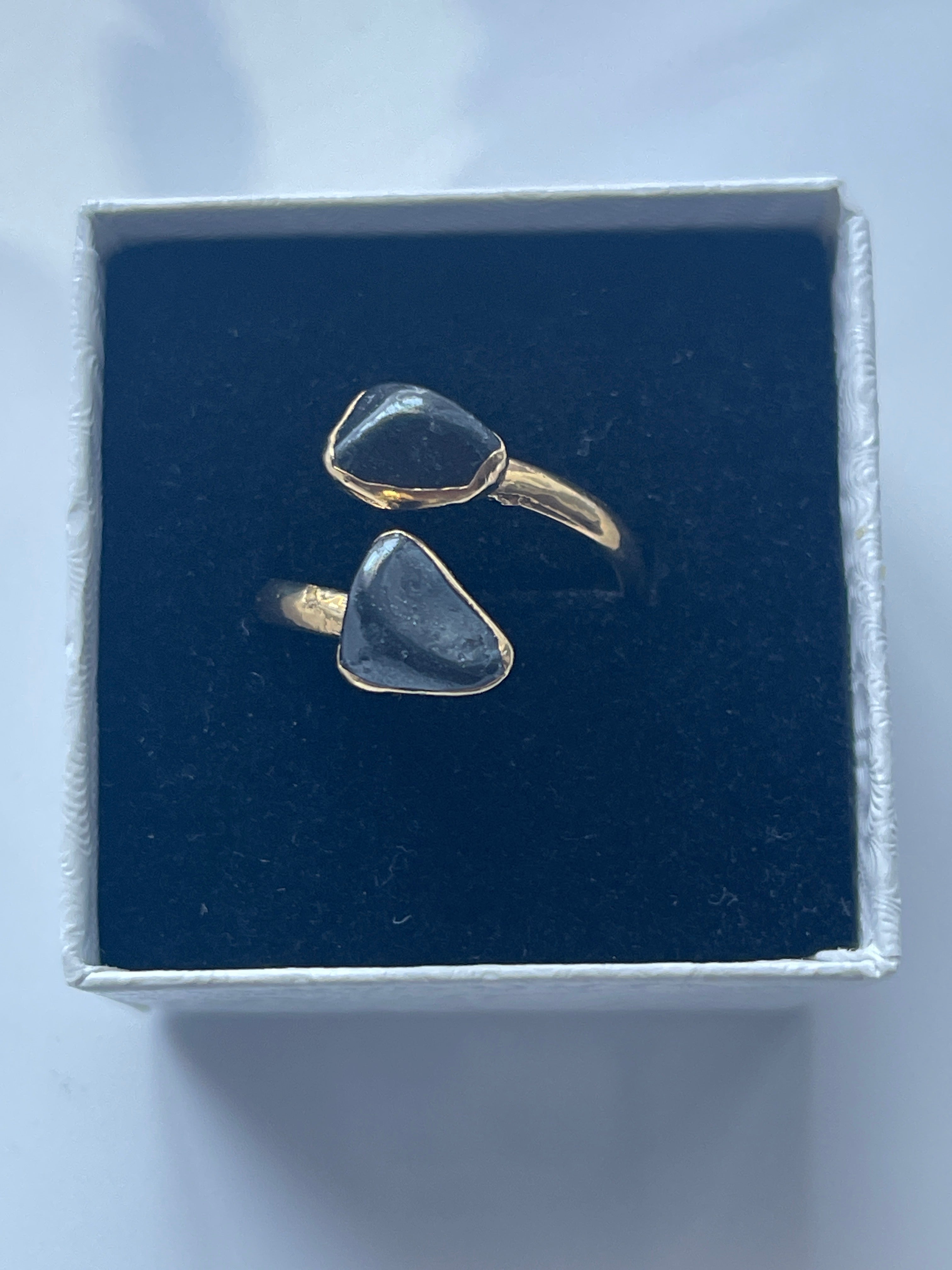 Hematite Adjustable Ring Gold Plated inside a black and white jewelry box
