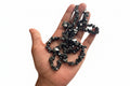 Hand holding a cluster of dark gray crystals known as Hematite with a white background
