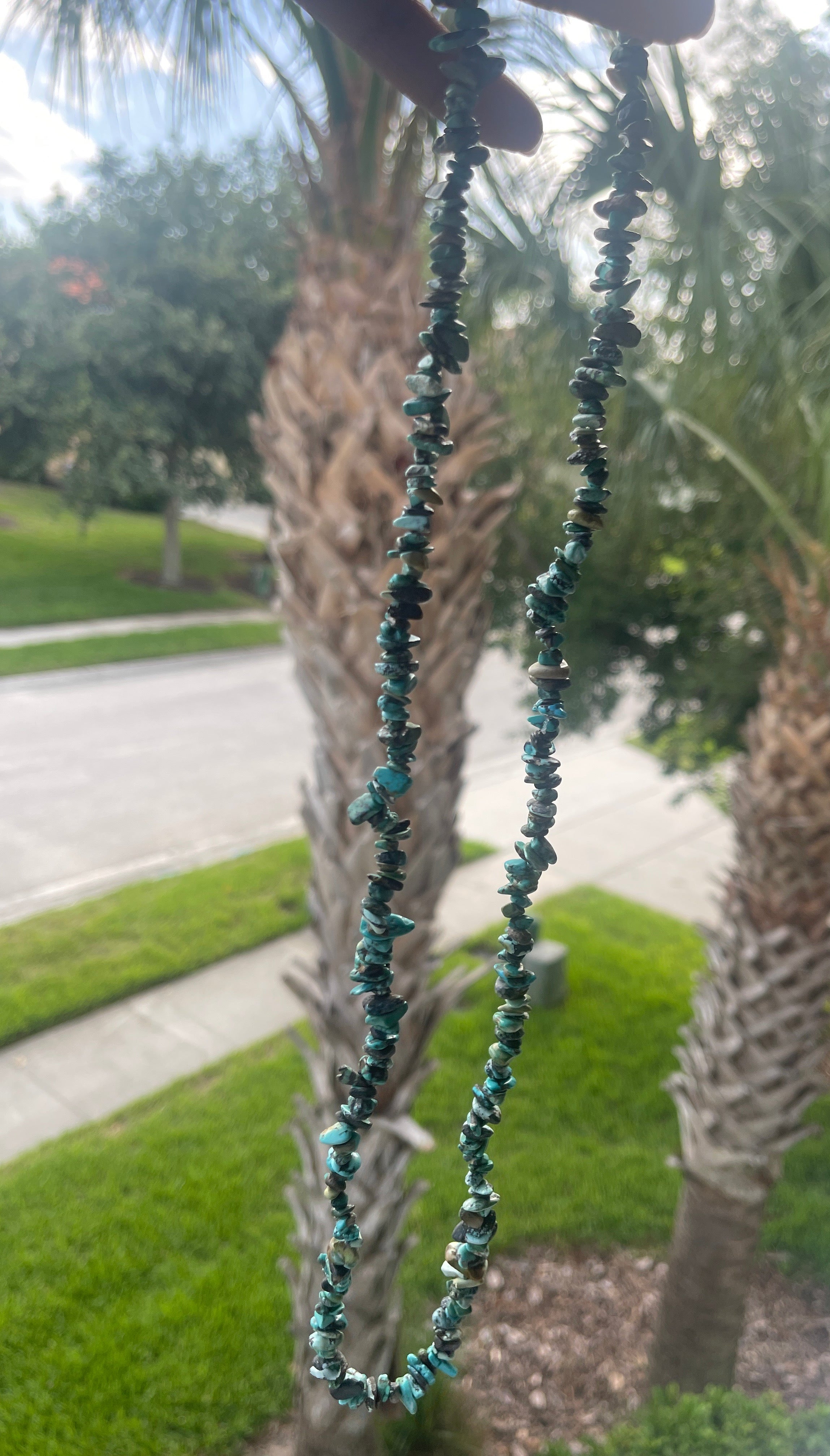 Hubei_Turquoise_Necklace_30-32_Inches Necklace with blue beads against a palm tree background