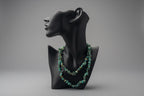 Black display with a green beaded Hubei_Turquoise_Necklace_30-32_Inches necklace in front of a gray backdrop. 