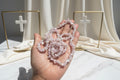 Hand holding a string of small, round, pink Kunzite_Chip_Bead_Necklaces_30-32_Inches beads against a blurred natural background