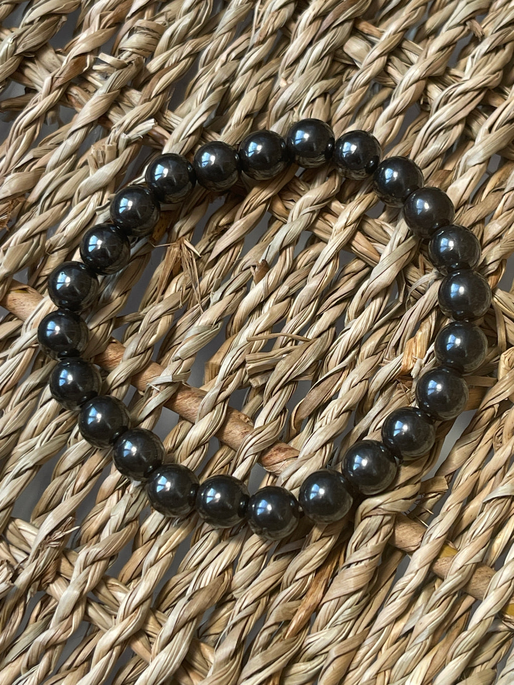 Magnetic Hematite Bracelet Black beaded bracelet on a woven surface