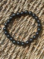 Magnetic Hematite Bracelet Black beaded bracelet on a woven surface