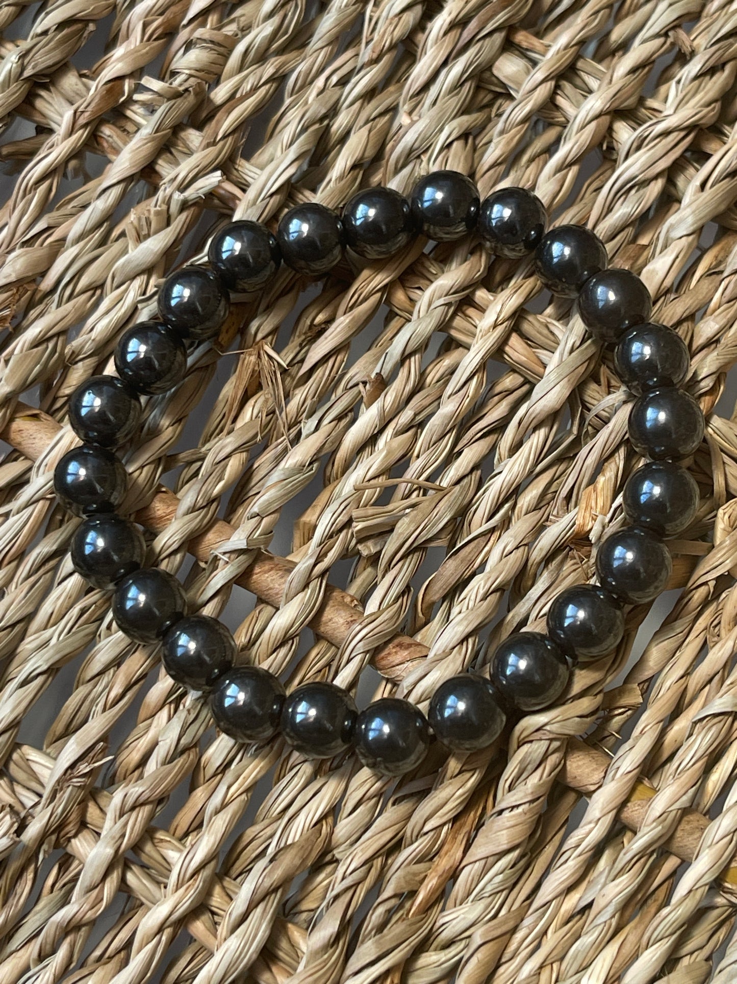 Magnetic Hematite Bracelet Black beaded bracelet on a woven surface