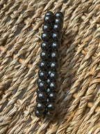 Magnetic Hematite Bracelet Row of black beads on a textured woven surface