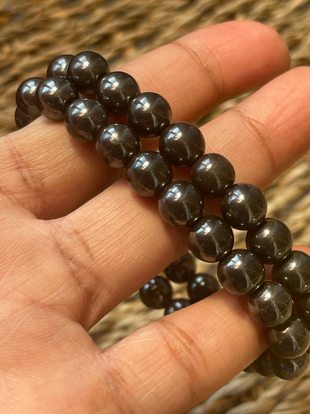 Magnetic Hematite Bracelet  Black beaded bracelet held in a hand with a blurred background