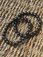 Magnetic Hematite Bracelet Black beaded necklace on a woven surface