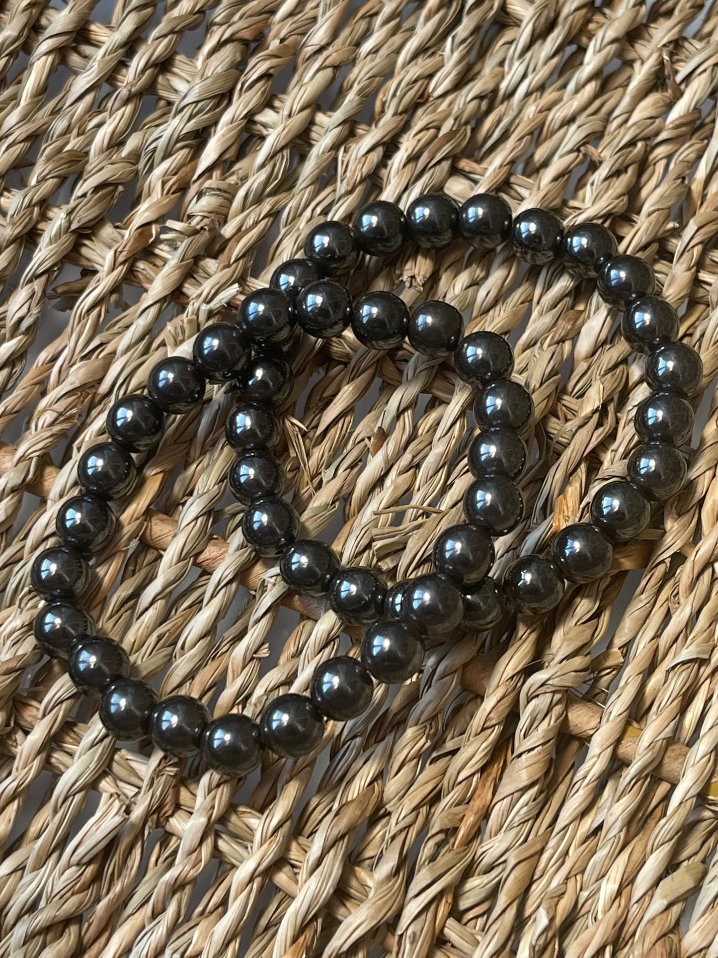 Magnetic Hematite Bracelet Black beaded necklace on a woven surface