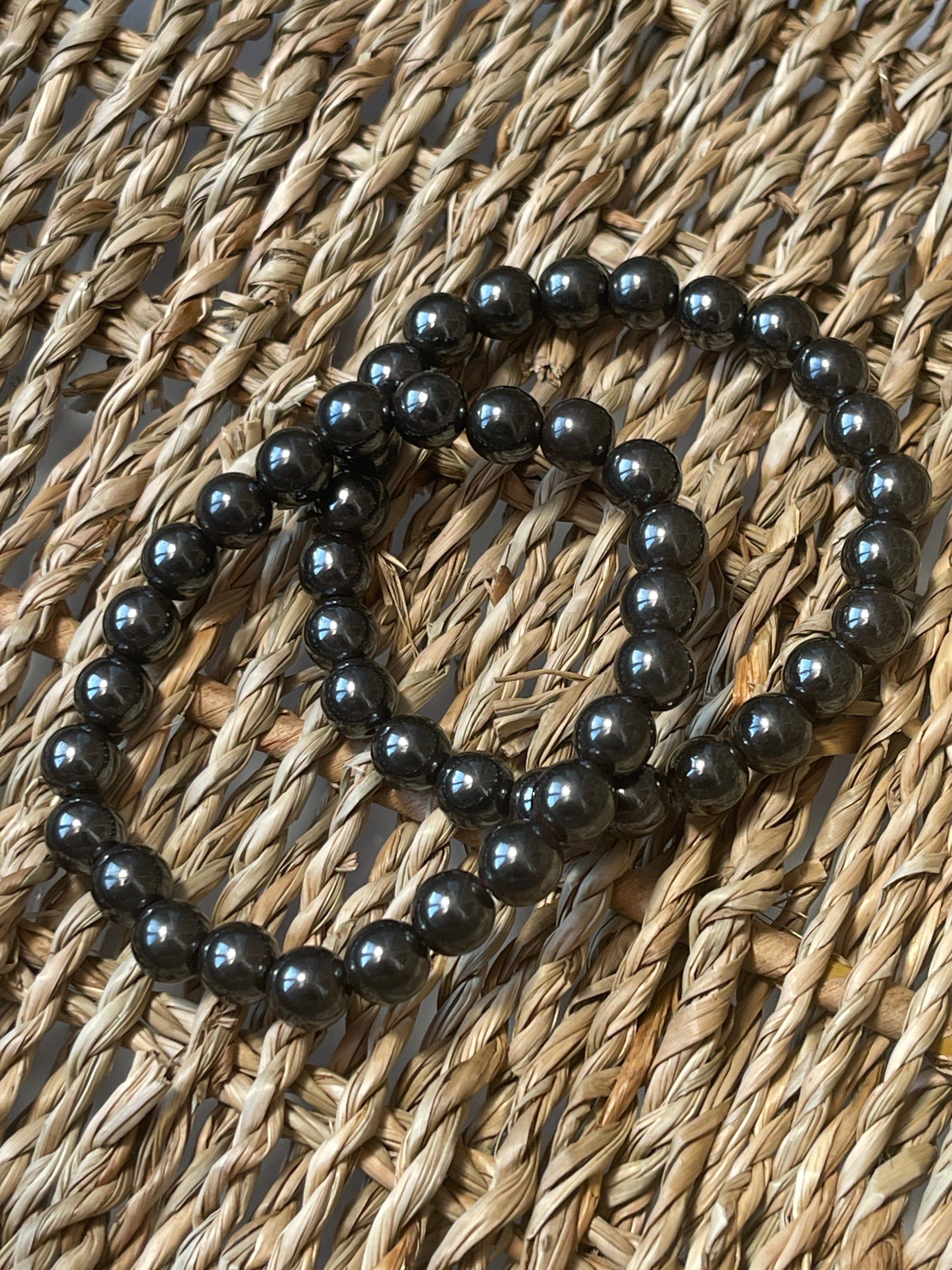 Magnetic Hematite Bracelet Black beaded necklace on a woven surface