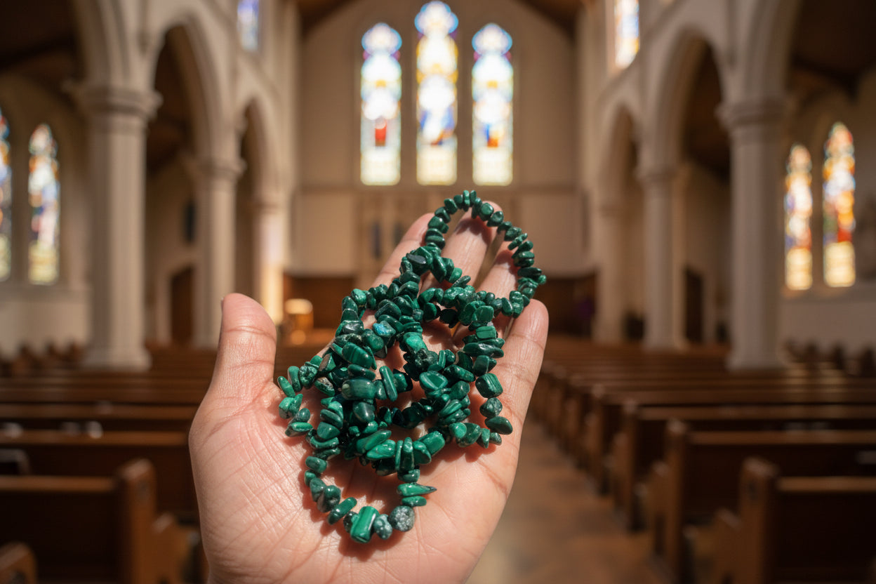 Malachite_Necklace_30-32_Inches Green bead necklace held in a hand with a blurred chapel background