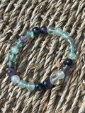 Multi Color Fluorite 8mm Bracelet. Multicolored beaded bracelet on a woven surface