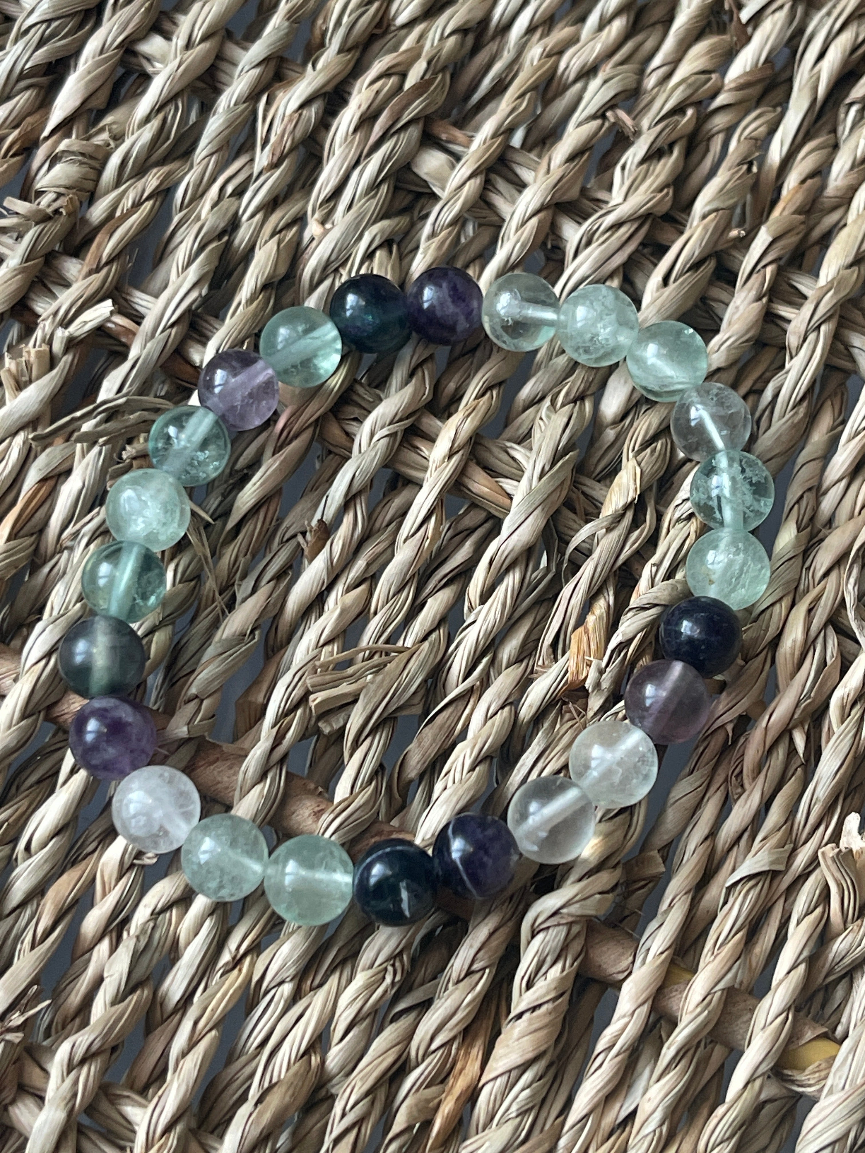 Multi Color Fluorite 8mm Bracelet. Multicolored beaded bracelet on a woven surface