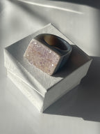 Close-up of a textured cylindrical object with a metallic sheen on a reflective surface. Natural Agate Druzy Ring Pure Energy Crystals Florida
