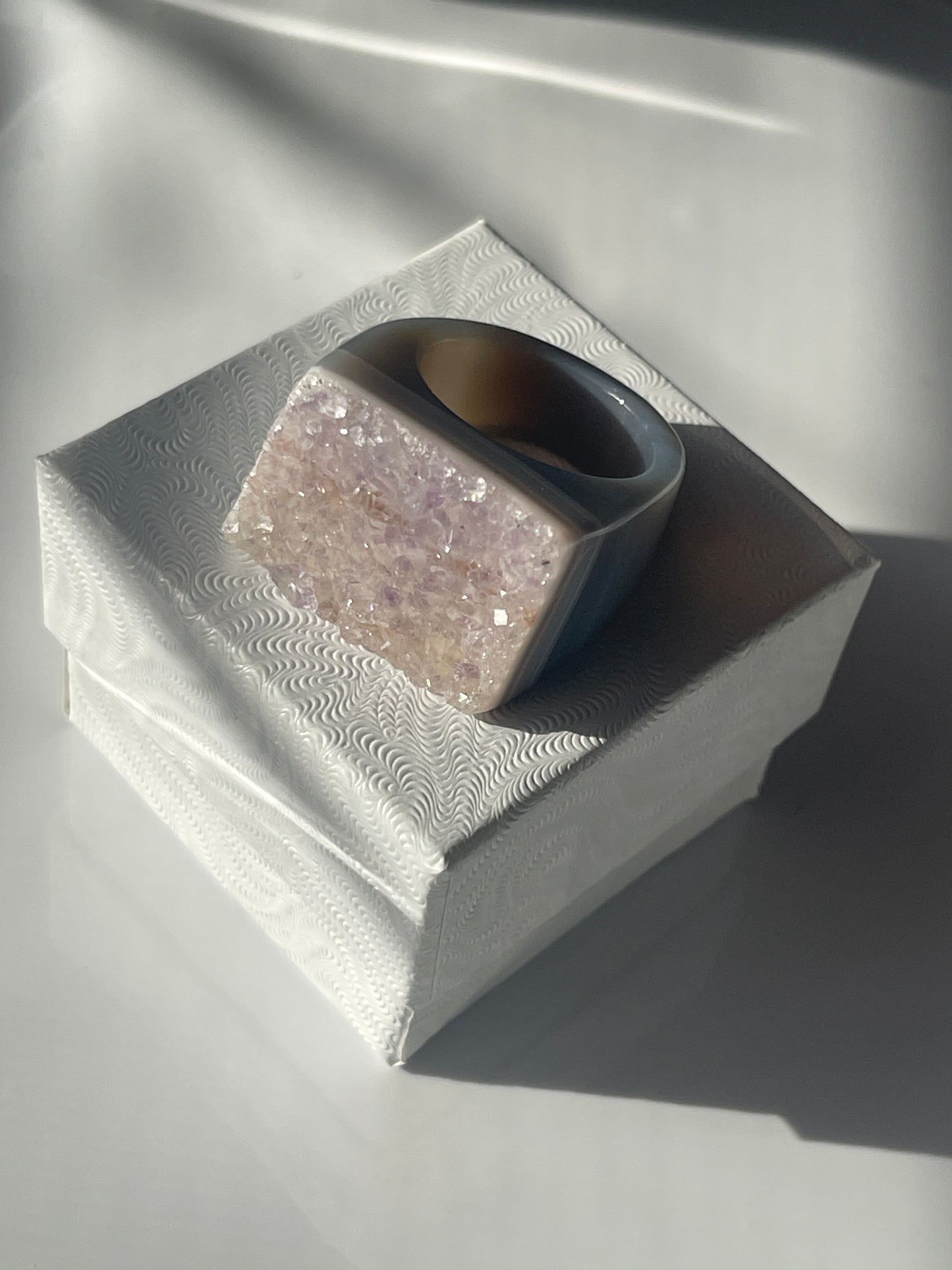 Close-up of a textured cylindrical object with a metallic sheen on a reflective surface. Natural Agate Druzy Ring Pure Energy Crystals Florida

