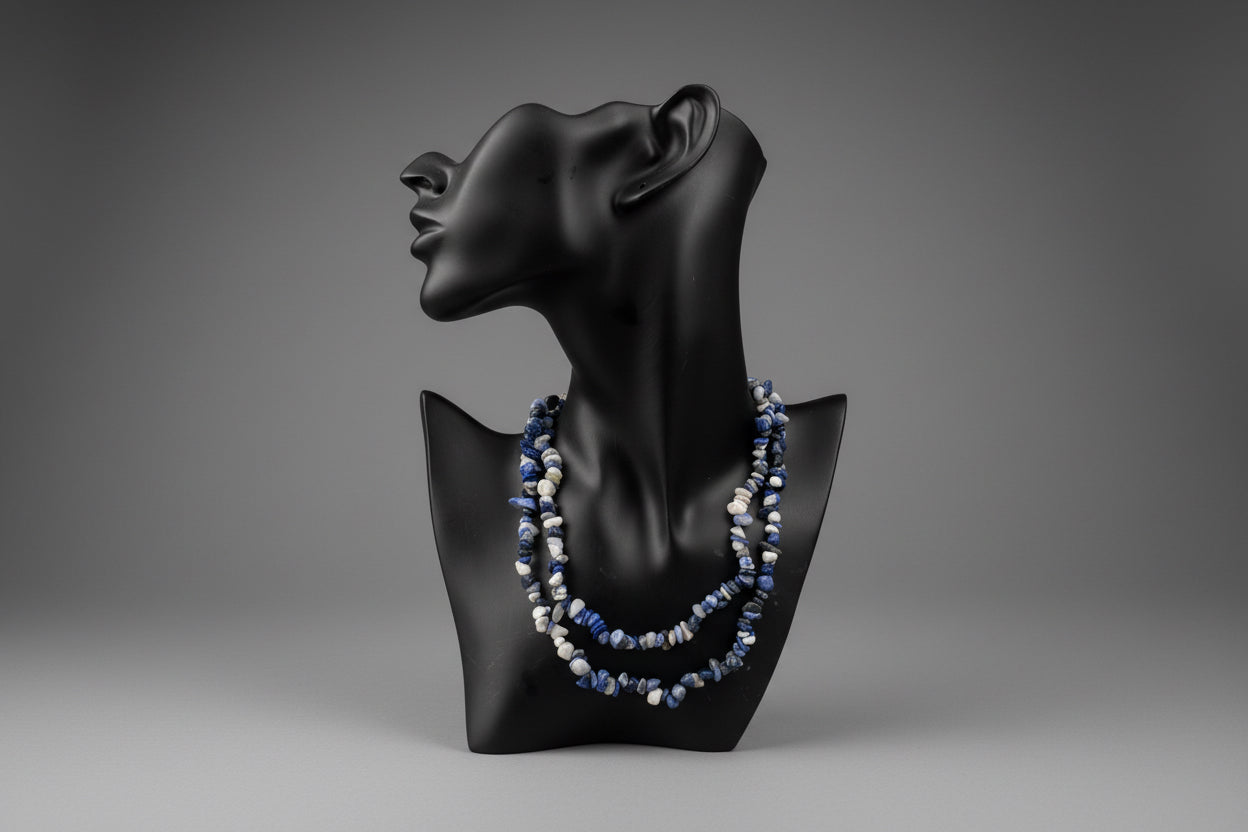 Black necklace jewelry display stand with a blue beaded Natural_sodalite_chip_necklace on a blurred studio background