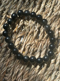Black and gray beaded bracelet on a woven surface