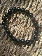 Black and gray beaded bracelet on a woven surface