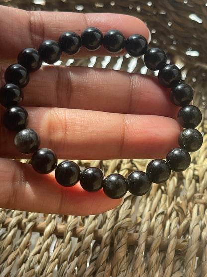 Black and gray beaded bracelet on a hand with a woven background