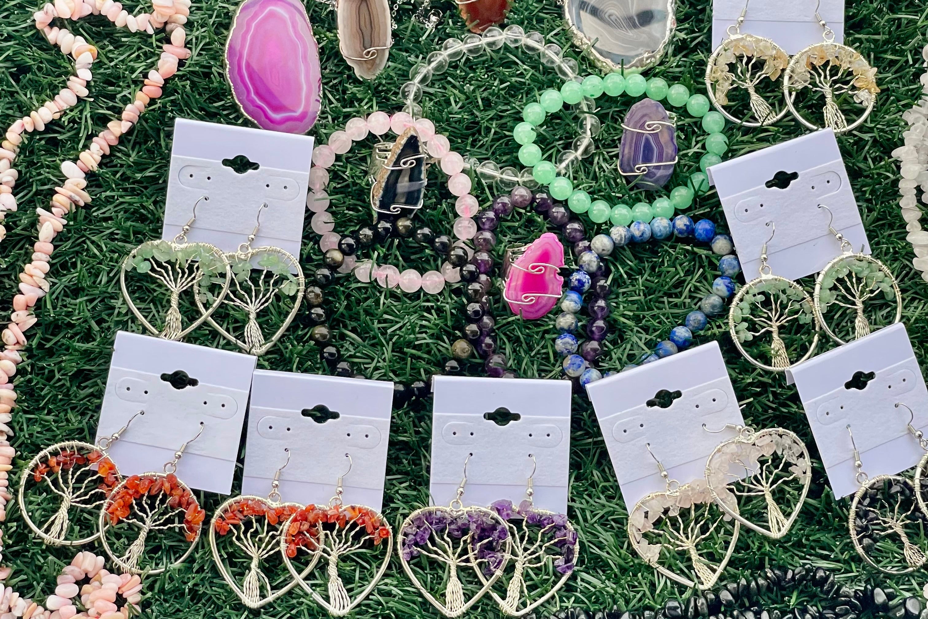 Jewelry set including necklaces, bracelets, and earrings on display cards against a grass background.