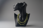 Black mannequin bust with a green necklace on a gray background