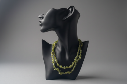 Black mannequin bust with a green necklace on a gray background