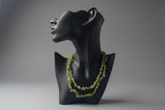 Black mannequin bust with a green necklace on a gray background
