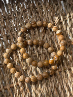 Picture Jasper beads arranged in a circular pattern on a woven surface