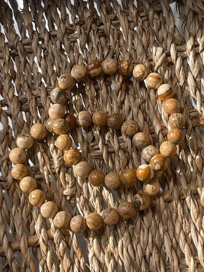 Picture Jasper beads arranged in a circular pattern on a woven surface