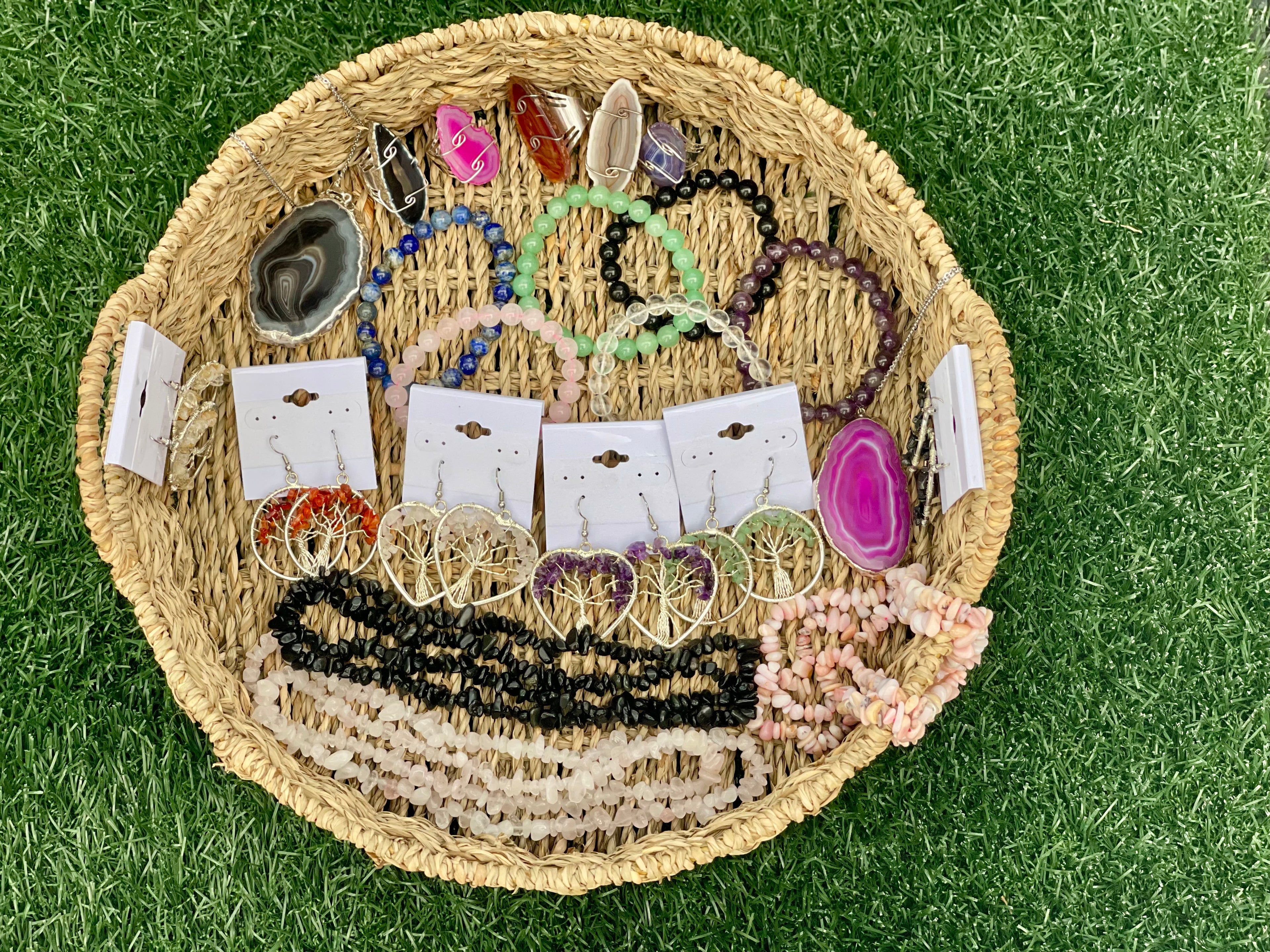 Woven basket with various necklaces and pendants on a grassy background
