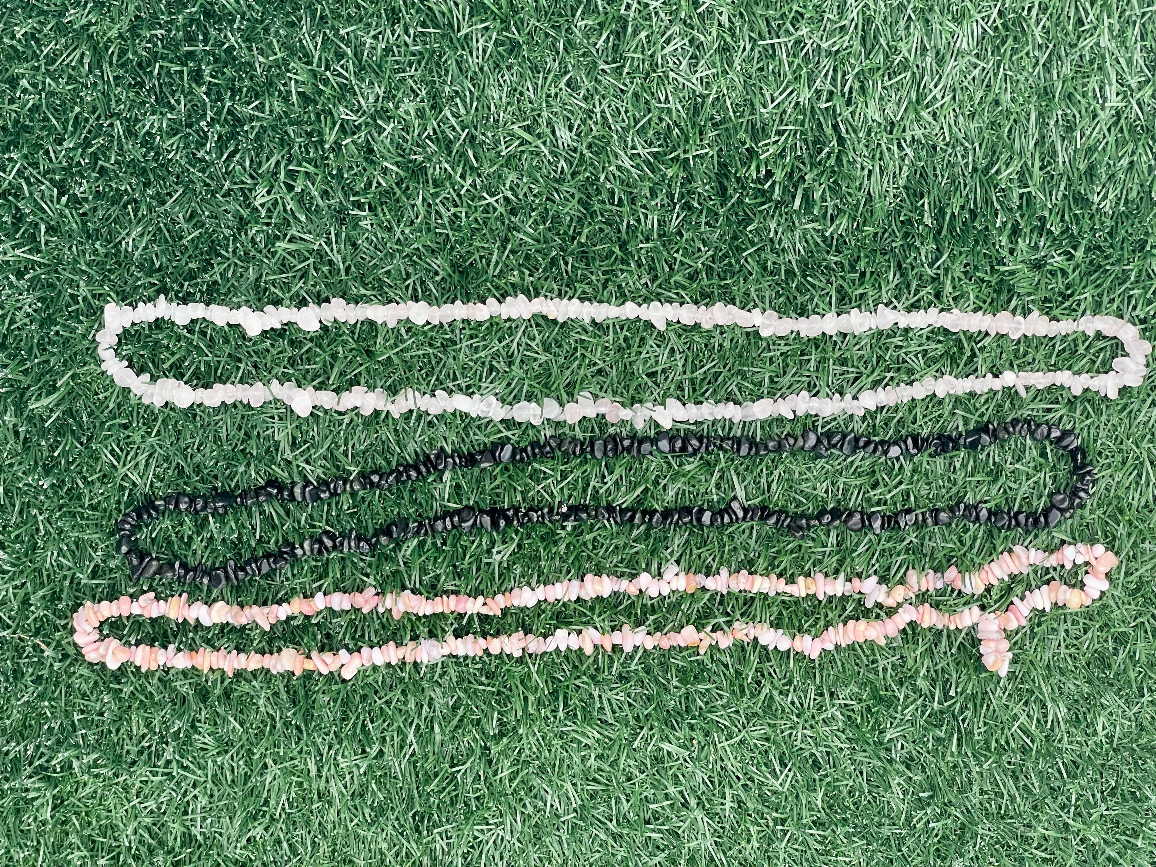 Three colorful crystal necklaces on a grassy background