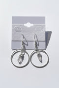 Quartz Point Circle Earrings, Silver hoop earrings with a small pendant on a gray surface