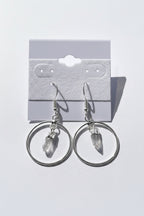Quartz Point Circle Earrings, Silver hoop earrings with a small pendant on a gray surface