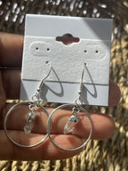 Quartz Point Circle Earrings, Clear crystal hoop earrings held by a hand with a branded card in the background.