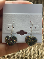 Rainbow Heart Coated Amethyst Earrings, Heart-shaped earrings on a white card held by a hand with a wicker background