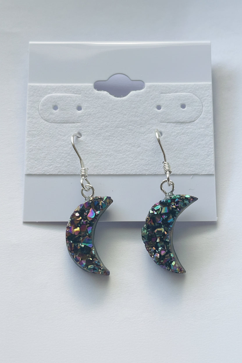 Rainbow Moon Amethyst Coated Earrings, Pair of glittery crescent moon earrings on a gray card.