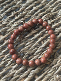Red beaded bracelet on a textured woven surface