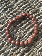 Red beaded bracelet on a textured woven surface