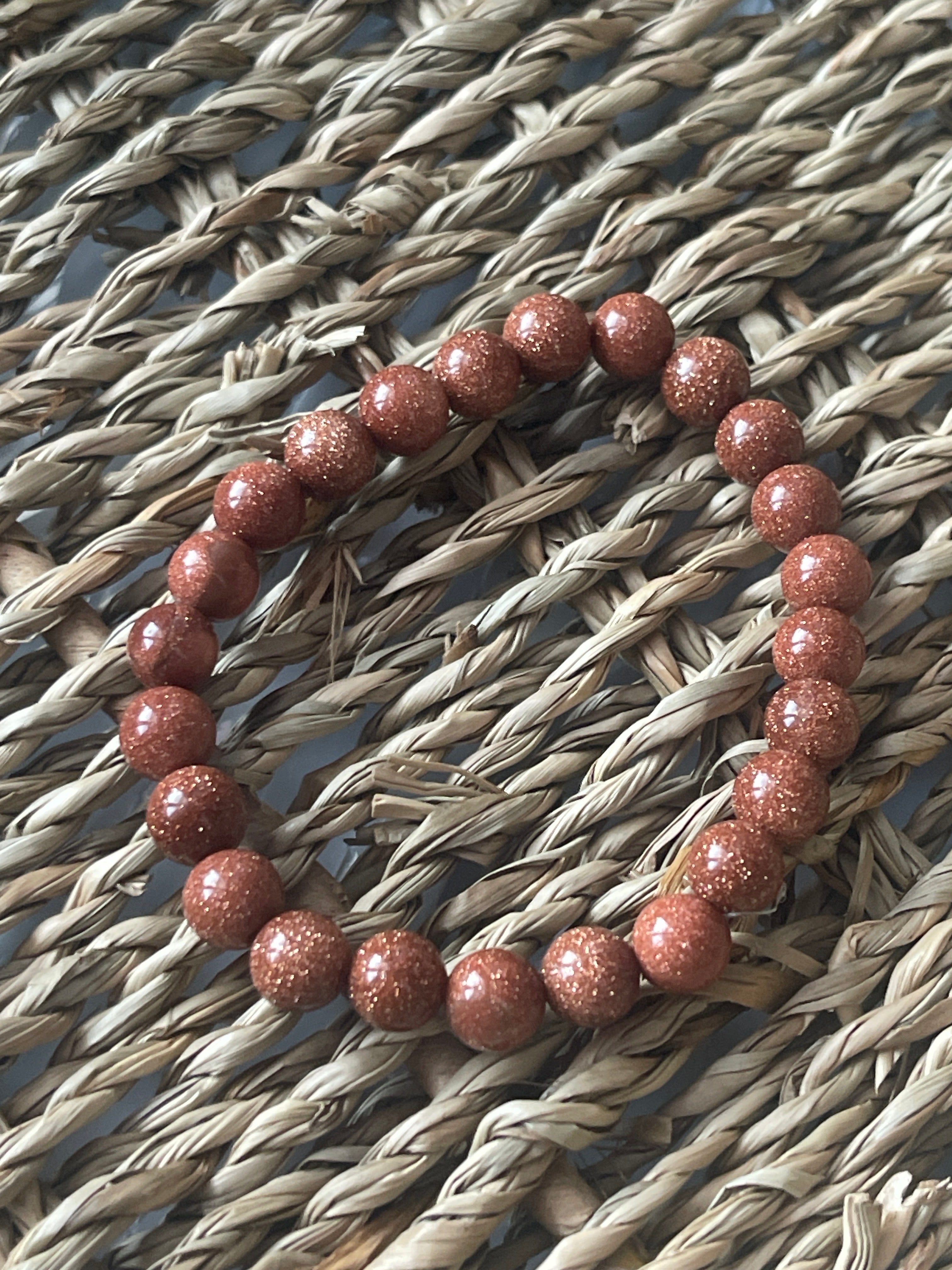 Red beaded bracelet on a textured woven surface
