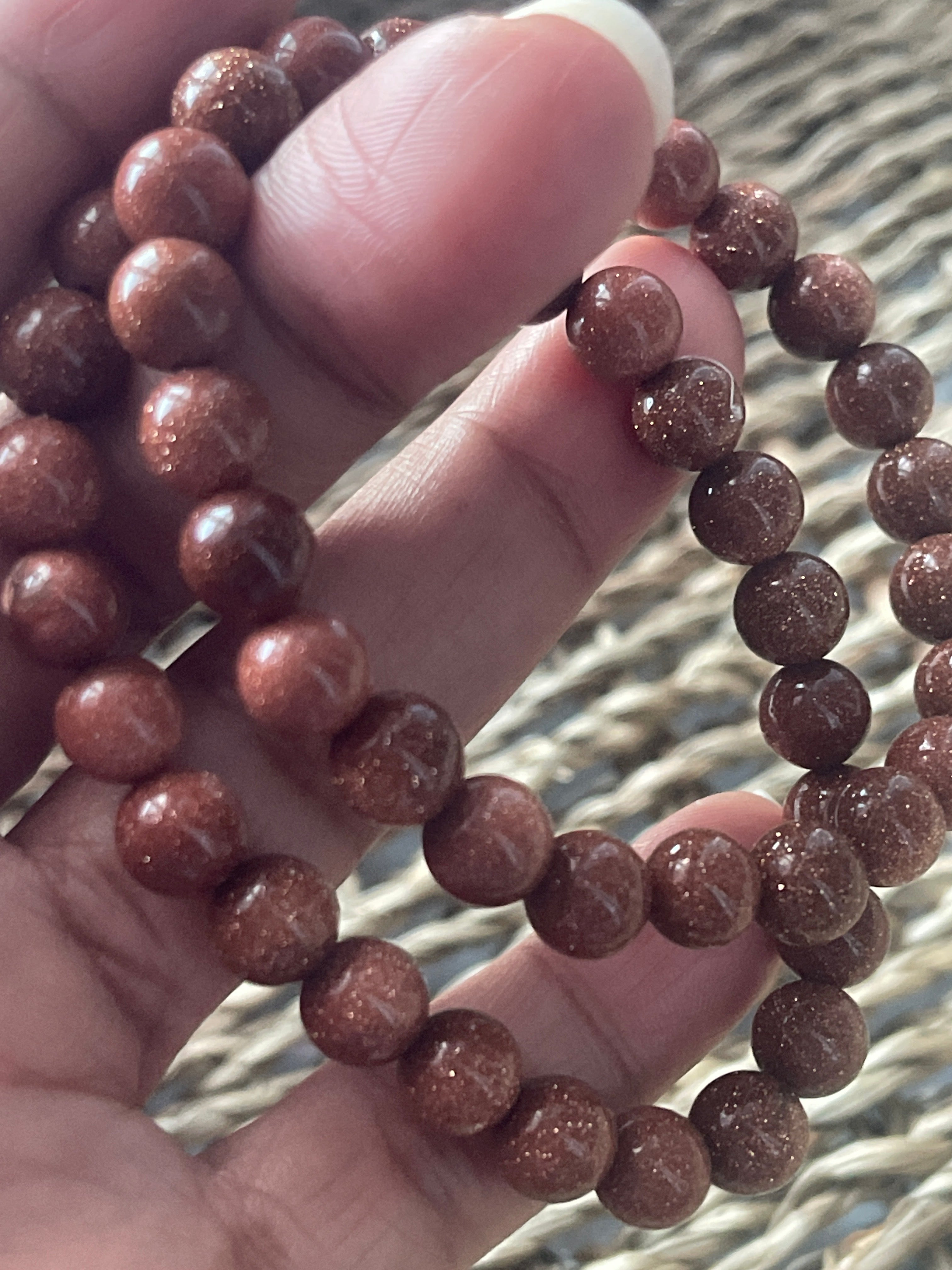 Close-up of a hand holding a red beaded bracelet against a blurred background