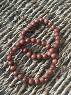 Red beaded bracelet on a textured woven surface