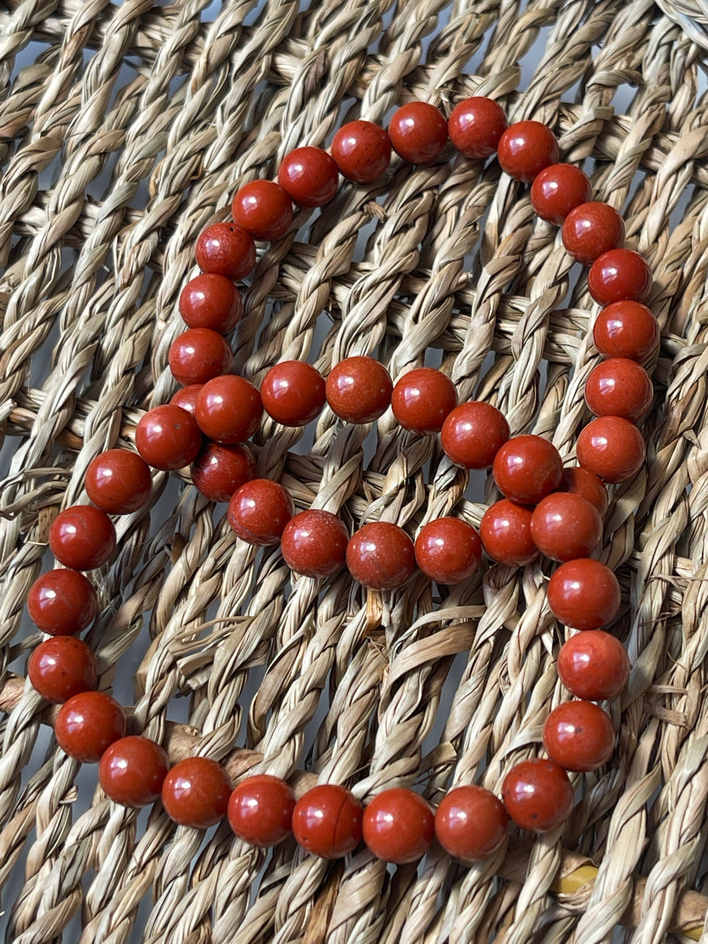 Red Jasper beaded bracelet on a woven surface