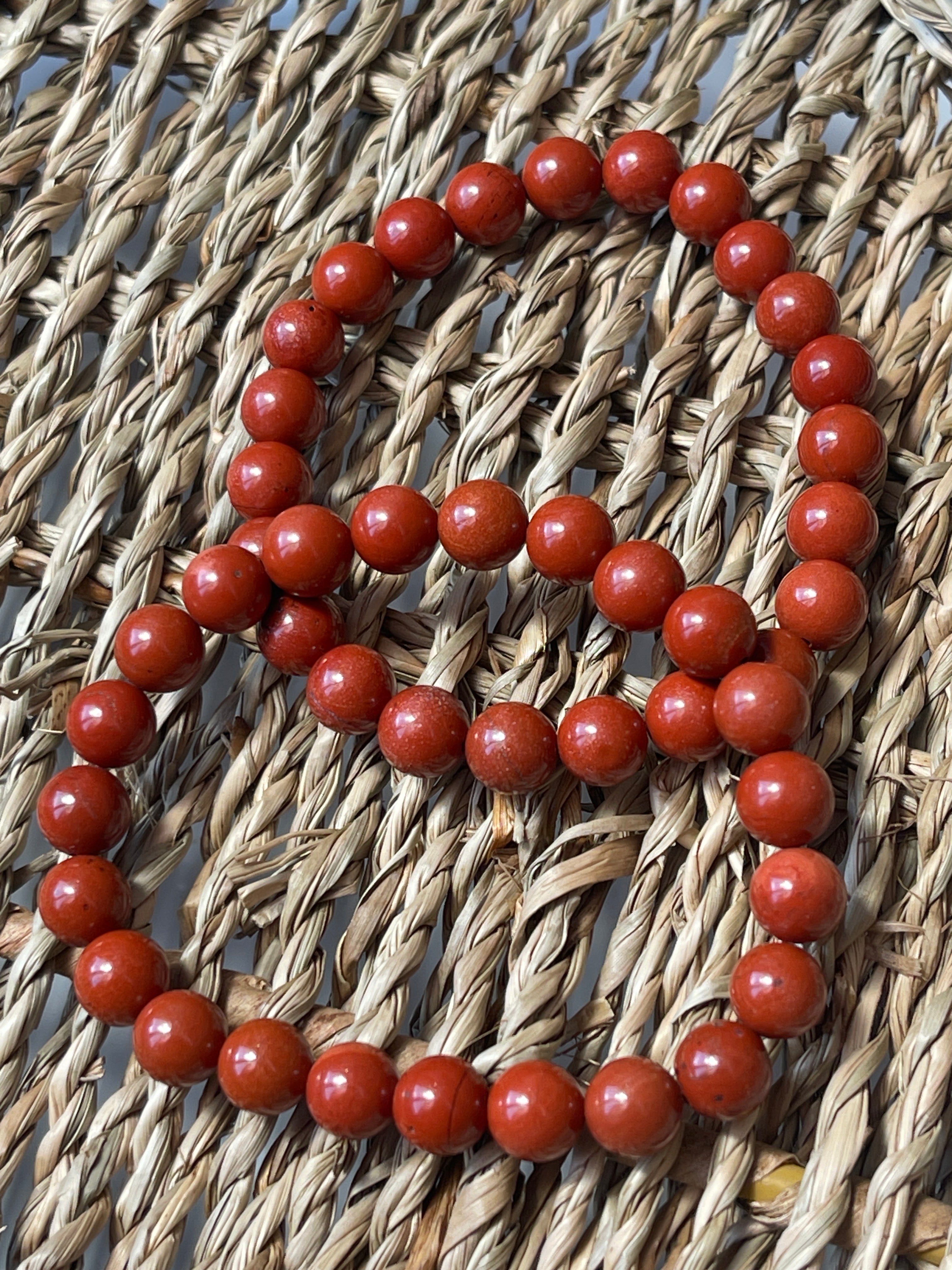 Red Jasper beaded bracelet on a woven surface