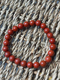 Red beaded bracelet on a woven surface